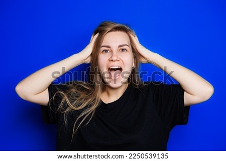 Happy beautiful woman without makeup in a black t-shirt showing different emotions on a blue background. Natural female beauty without cosmetics, naturalness. The concept of beauty