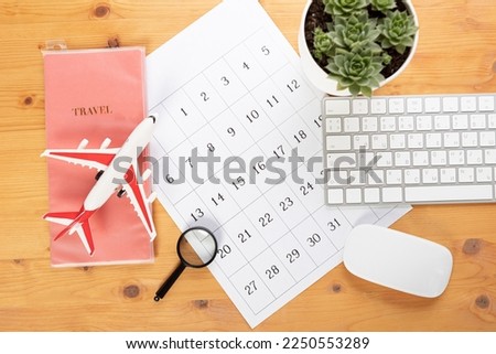 Calendar and reminders for work trips, travel and vacations. glider on desktop with airplane and magnifying glass and pen, keyboard. marking important dates and days in a diary at the office desk. 