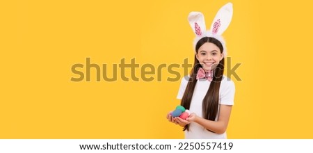 happy easter child girl in bunny ears and bow tie hold painted eggs, egg hunt. Easter child horizontal poster. Web banner header of bunny kid, copy space.