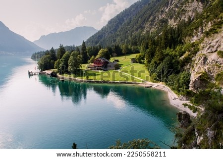 Stunning view of Achen lake, Achensee, Tirol Austria. Amazing nature, mountains around a green colored lake. Meadows full of grass, blue sky, family holiday in Austria.  Royalty-Free Stock Photo #2250558211