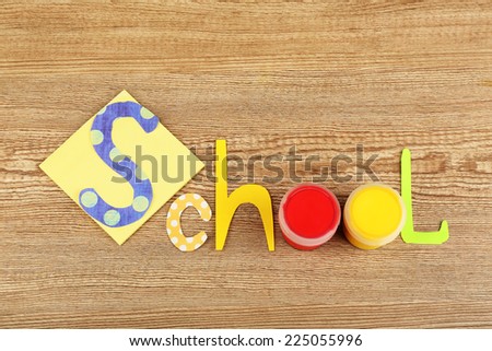 Inscription school lined of school supplies on wooden background
