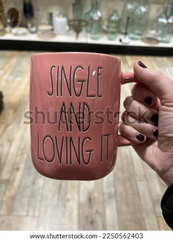 A woman holding a coffee mug that says "Single and Loving It".