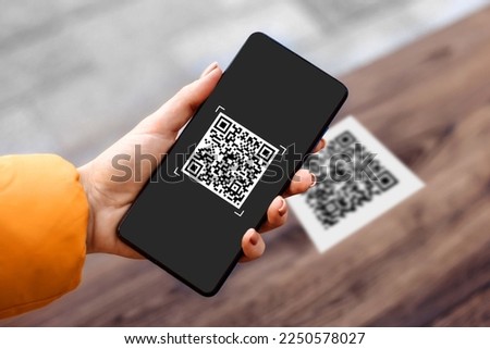 female hand holding black mobile phone with qr code on the screen. scanning the qr code Royalty-Free Stock Photo #2250578027