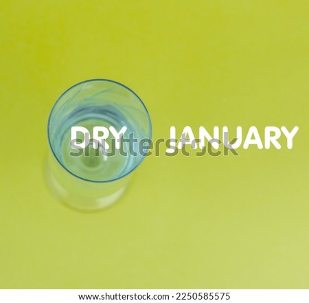 a glass goblet with water on a green background with copy space and the inscription Dry January.