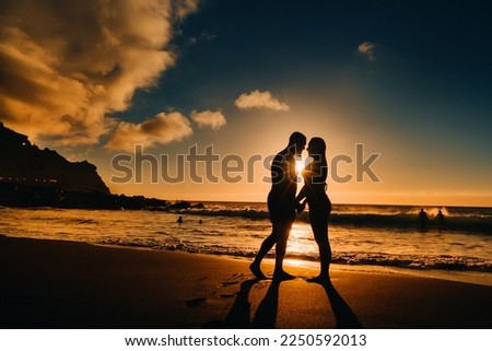 A couple in love is standing on the beach holding hands at sunset. The concept of a romantic trip.