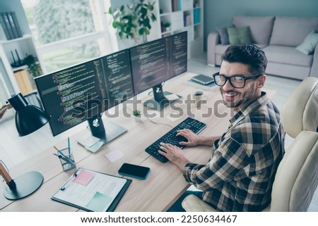 Photo of cheerful positive freelancer wear eyeglasses programming modern gadget application indoors workplace workstation loft