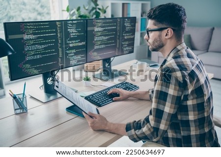 Photo of serious busy coder dressed eyewear holding list typing modern gadget indoors workplace workstation loft