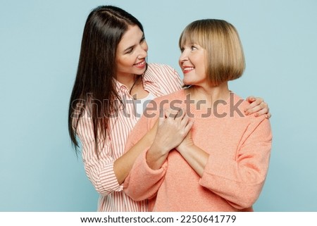 Cheerful smiling elder parent mom with young adult daughter two women together wearing casual clothes hugging cuddle looking to each other isolated on plain blue cyan background. Family day concept