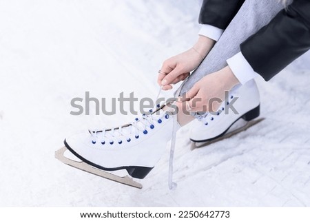 close-up view of white figure skating skates, worn on legs, young girl laces up, active holidays in winter