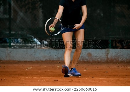 Close-up view of athlete female player in sportswear holding racket and ball playing tennis and prepare to serve on the court.