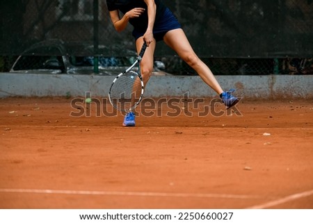 close-up view of legs of woman tennis player with tennis racket on outdoor tennis court. Tennis player prepares to serve during the match.