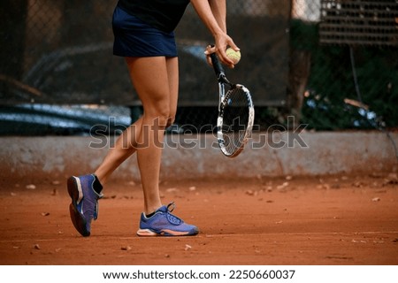 close-up view of legs of woman tennis player with tennis racket and ball in her hand. Tennis player prepares to serve during the match.