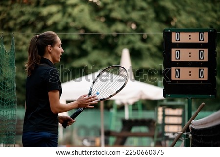 side view of athletic female tennis player with tennis racket in her hand. Outdoor tennis practice.