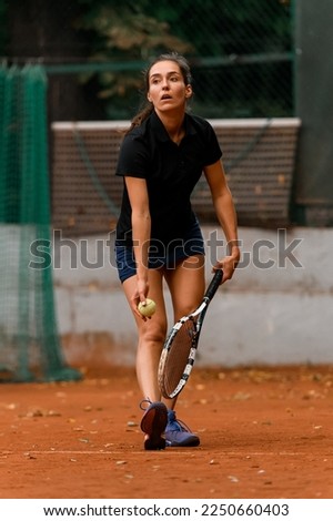 healthy active female tennis player holding ball and racket and preparing to serve. Training at outdoor tennis court.