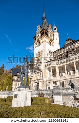 Detail of beautiful Peles Castle in Sinaia with the statue of King Carol I of Romania in front. Early autumn morning in Transylvania, Brasov region, Romania.