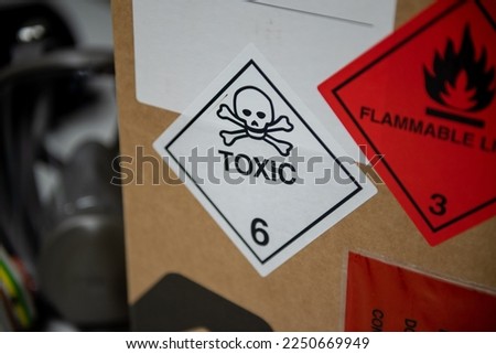 Toxic and flammable symbol on a box with a mask in the background.