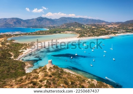 Aerial view of beautiful sandy beach, old tower on the hill, sea bays, mountains at summer sunny day. Porto Giunco in Sardinia, Italy. Top view of blue sea with clear water, white sand, mountains Royalty-Free Stock Photo #2250687437