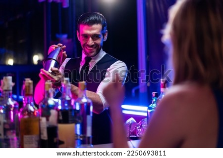 Caucasian profession bartender making a cocktail for women at a bar. Attractive barman pouring mixes liquor ingredients cocktail drink from cocktail shaker into the glass at night club restaurant. Royalty-Free Stock Photo #2250693811