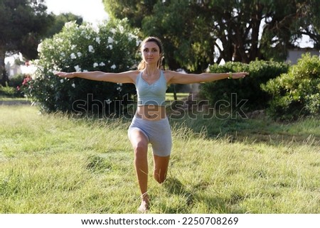 Pretty woman doing yoga in morning park. Healthy lifestyle outdoor conception. Sport. Woman nature portrait doing exercises. Healthy lifestyle.