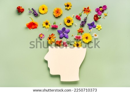 Human head symbol and flowers on blue background. World mental health day concept Royalty-Free Stock Photo #2250710373