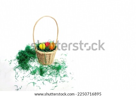 happy easter basket with green grass and painted eggs isolated on white