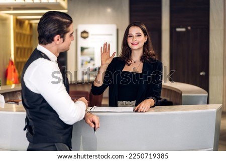 Young handsome businessman talking and check in Register information with woman receptionist worker standing in counter hotel reception counter desk at lobby modern hotel