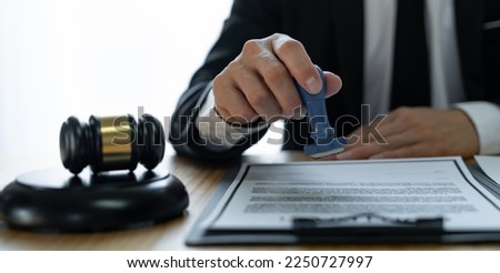 Young Asian legal advisor or lawyer doing document approval stamp Business agreements regarding real estate financial documents at the office.