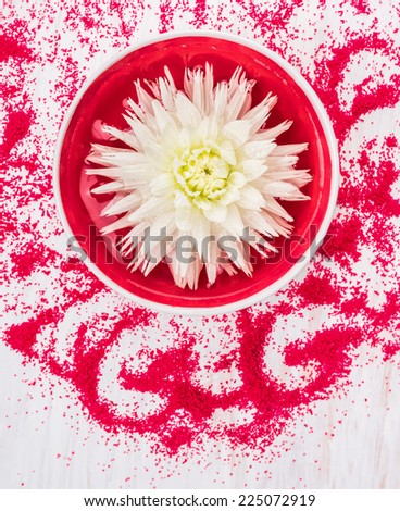 White Flower in red bowl with water and bath salt for spa, top view