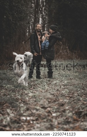 New born family photo shoot in the fall by the woods with family dog running off