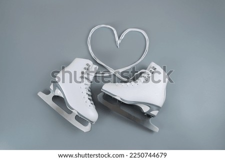 Pair of white figure ice skates shoes on blank gray background, and laces form a heart shape