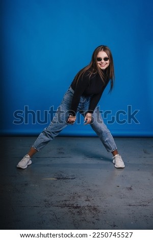 Full length photo of lovely young lady wearing casual outfit smiling and dancing isolated on blue color background