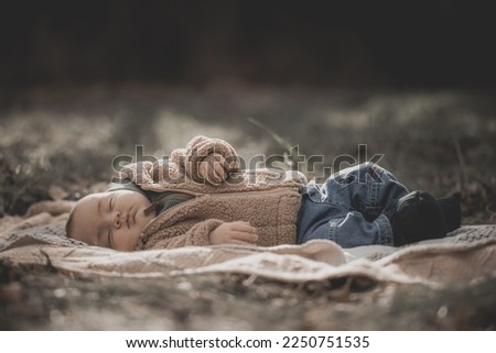 New born fall family photo shoot in forest. New born full body wearing fuzzy jacket and jeans with booties on blanket