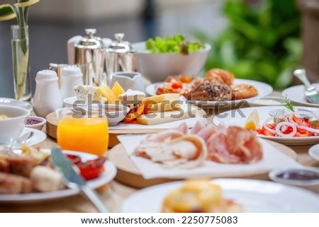 Table full of various fresh food in luxury modern restaurant. Delicious dishes, cold cuts, salmon, omelette, pastries, juices, cheese. Delicious and lavish breakfast or morning meal in high-end hotel Royalty-Free Stock Photo #2250775083