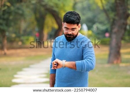 Young indian man looking time in wristwatch. Royalty-Free Stock Photo #2250794007