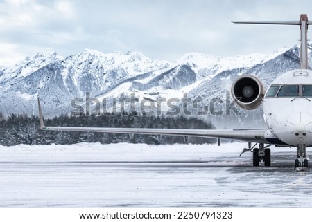 Front view of the luxury private jet on the winter airport apron on the background of high picturesque mountains Royalty-Free Stock Photo #2250794323