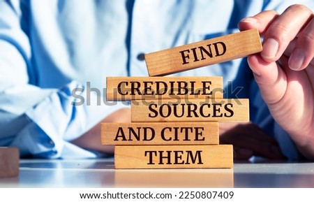 Close up on businessman holding a wooden block with "Find credible sources and cite them" message Royalty-Free Stock Photo #2250807409