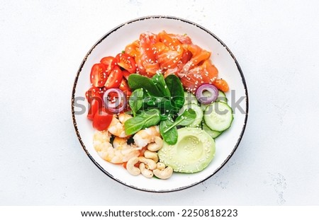 Salmon salad for ketogenic diet with shrimp, avocado, spinach, cucumber, tomato, cashew nuts, sesame. Low-carbohydrate breakfast rich in healthy fats. White table background, top view Royalty-Free Stock Photo #2250818223