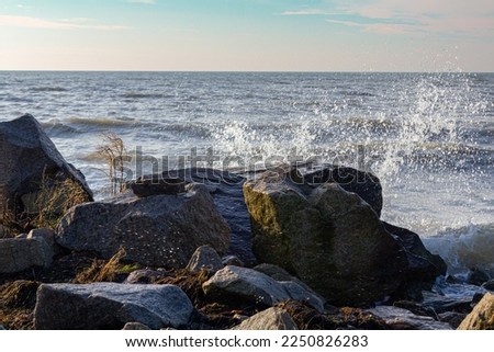 a beautiful seashore with a wave and big stones, the waves break on the rocks