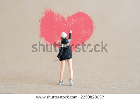 Miniature people, Artist holding dispenser and spraying with red heart shapes, Valentine day concept