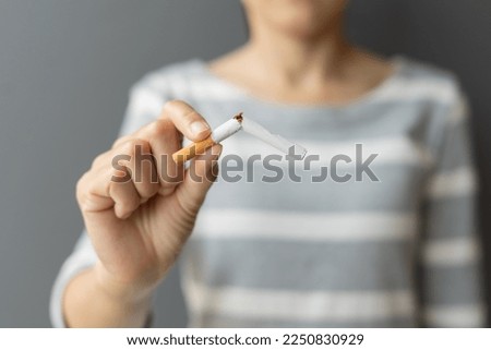 Portrait young woman holding broken cigarette in hands. Happy female quitting refusing smoking cigarettes. Quit bad habit, Stop smoking cigarettes, health care concept. No smoking campaign.