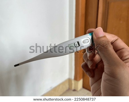 Asian male hands holding a digital thermometer with error sign on the display screen