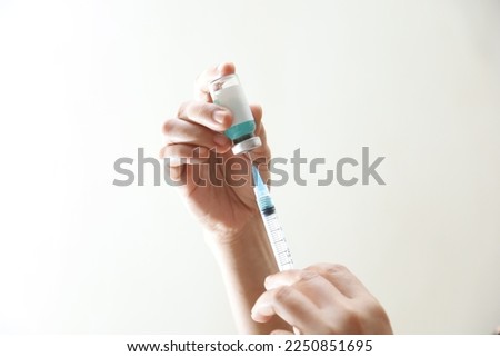 female hand holding medicine bottle and syringe for vaccine to patient.  Nurse using a syringe to vaccinate a patient for influenza protection.  Treatment medicine concept. Royalty-Free Stock Photo #2250851695