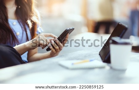 Asian freelance woman working and meeting on her smart phone on wooden table at outdoor cafe. Entrepreneur woman working for her new business concept.
