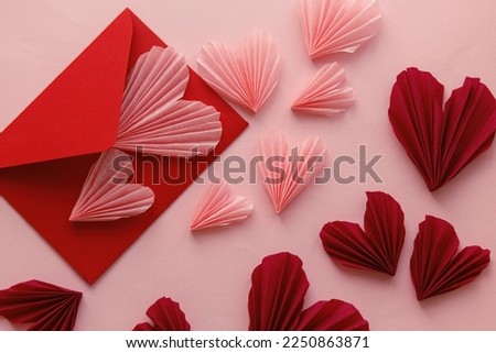 Happy Valentine's day! Stylish pink hearts and red envelope flat lay on pink paper background. Modern Valentines day composition. Love letter concept.