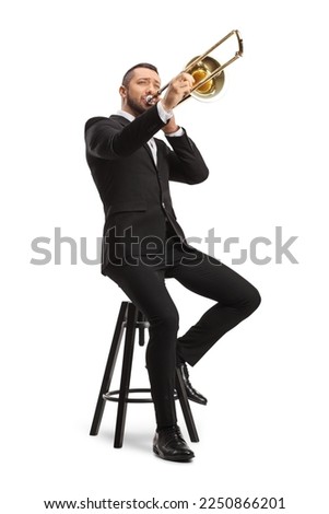 Male musician sitting on a chair and playing a trombone  isolated on white background Royalty-Free Stock Photo #2250866201