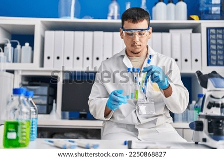 Young man scientist holding test tubes at laboratory