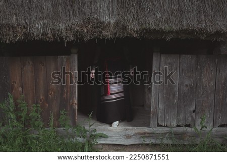 Ukrainian mythology aesthetic scenic photography. Picture of mysterious woman hiding in hut with straw roof on background. High quality wallpaper. Photo concept for ads, travel blog, magazine, article