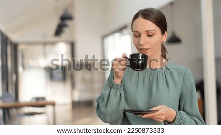 Smiling businesswoman leaning against whiteboard and drinking coffee