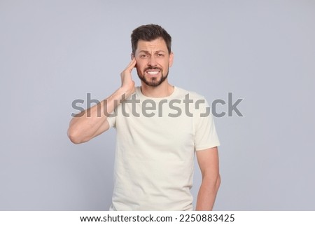 Man suffering from ear pain on grey background Royalty-Free Stock Photo #2250883425