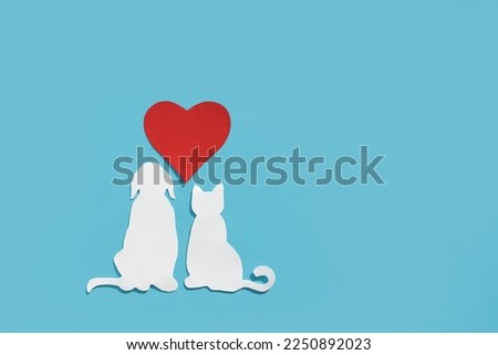 Paper silhouette of a cat, dog and red heart on a blue background. Flat lay, place for text. Veterinary care or animal care.